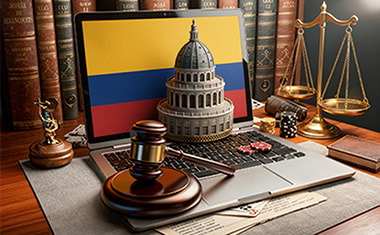 Portátil con una bandera de Colombia, un mazo judicial y una balanza sobre un escritorio.