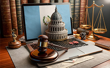 Portátil con una bandera de Guatemala, un mazo judicial y una balanza sobre un escritorio.