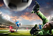 Un jugador dispara frente al portero en un partido de fútbol.