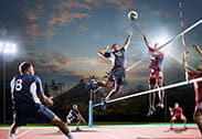 Dos jugadores saltan en frente de la red en un partido de voleibol.