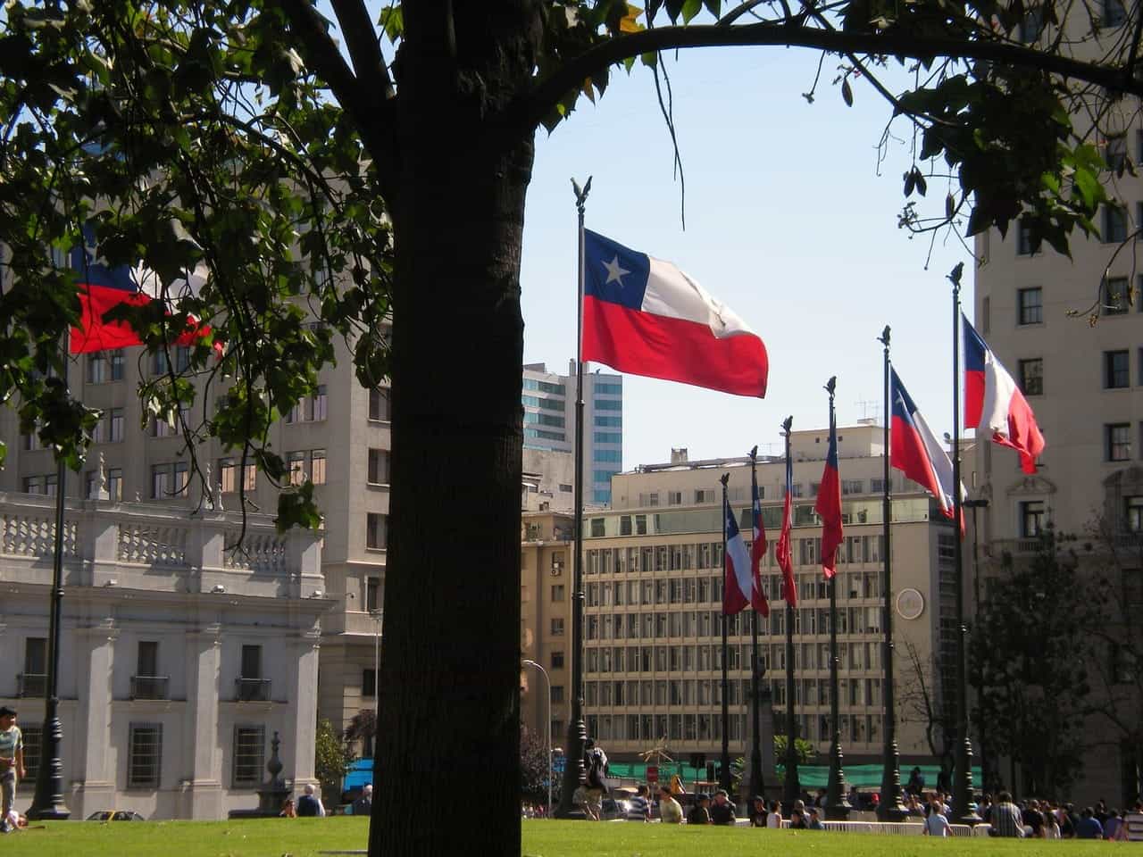 Banderas de Chile flameando frente a edificios públicos.
