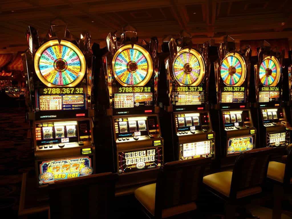 Cinco máquinas tragaperras de colores brillantes en un casino.