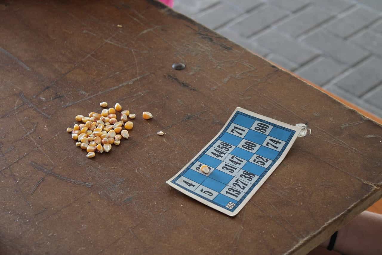 Cartón de bingo celeste con granos de maíz para jugar.