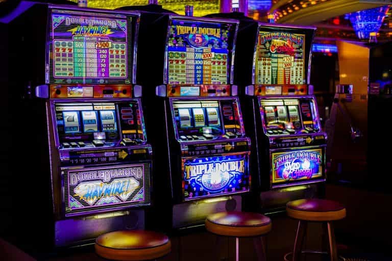 Tres máquinas tragaperras de colores brillantes en un casino.
