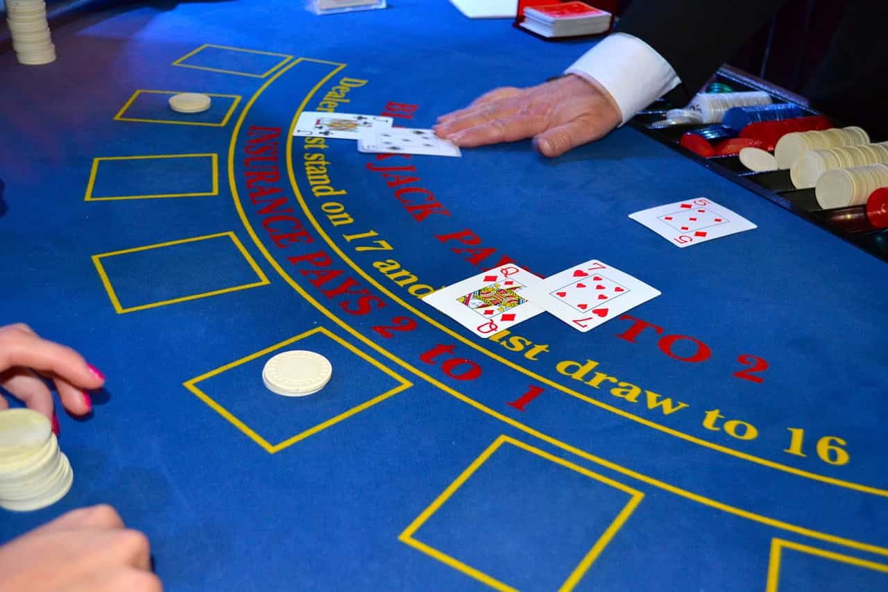 Mesa de blackjack en un casino con las manos del crupier visibles junto a las cartas.