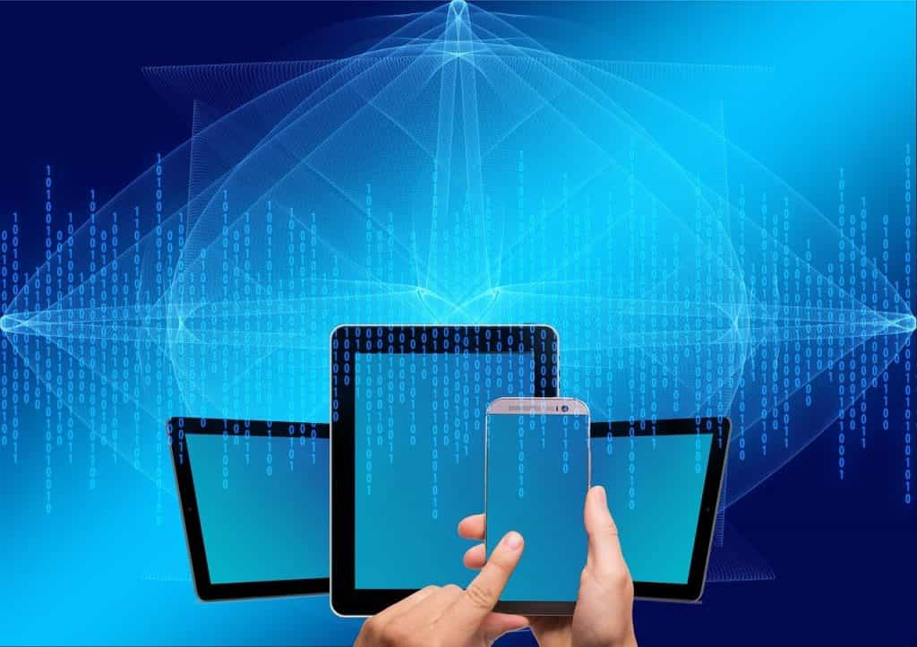 Tabletas y teléfonos inteligentes sobre fondo de código informático. Un dedo se apoya sobre la pantalla de un teléfono.