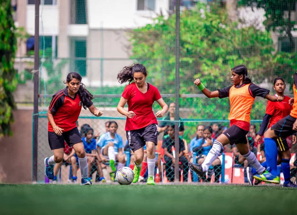 Mujeres con camisetas rojas jugando al fútbol.