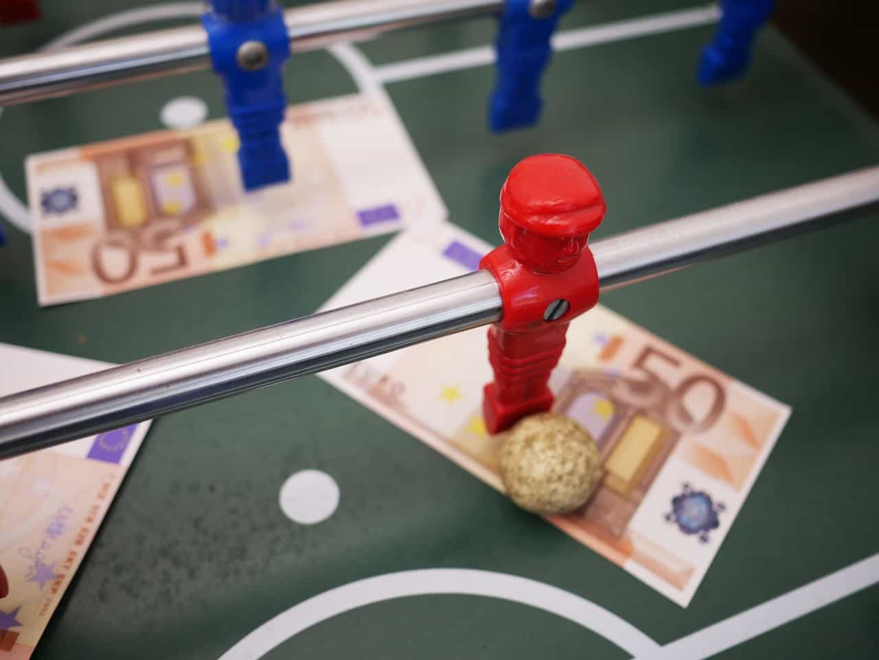 Mesa de futbolín con dos billetes de cincuenta euros bajos los jugadores.