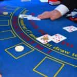Crupier repartiendo cartas en una mesa de juego en un casino.