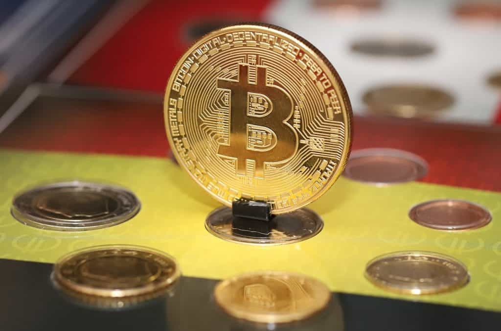 Moneda acuñada con el logo de bitcoin parada sobre una ranura.