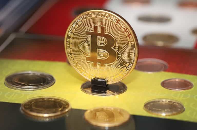 Moneda acuñada con el logo de bitcoin parada sobre una ranura.