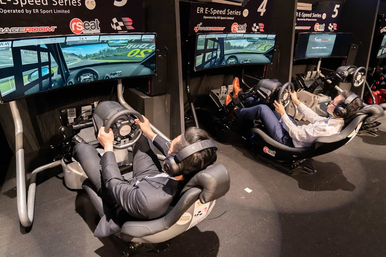 Dos personas sentadas en sus respectivos simuladores de carreras de autos de eSports.