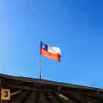 Bandera de Chile ondeando en un mástil en un techo.