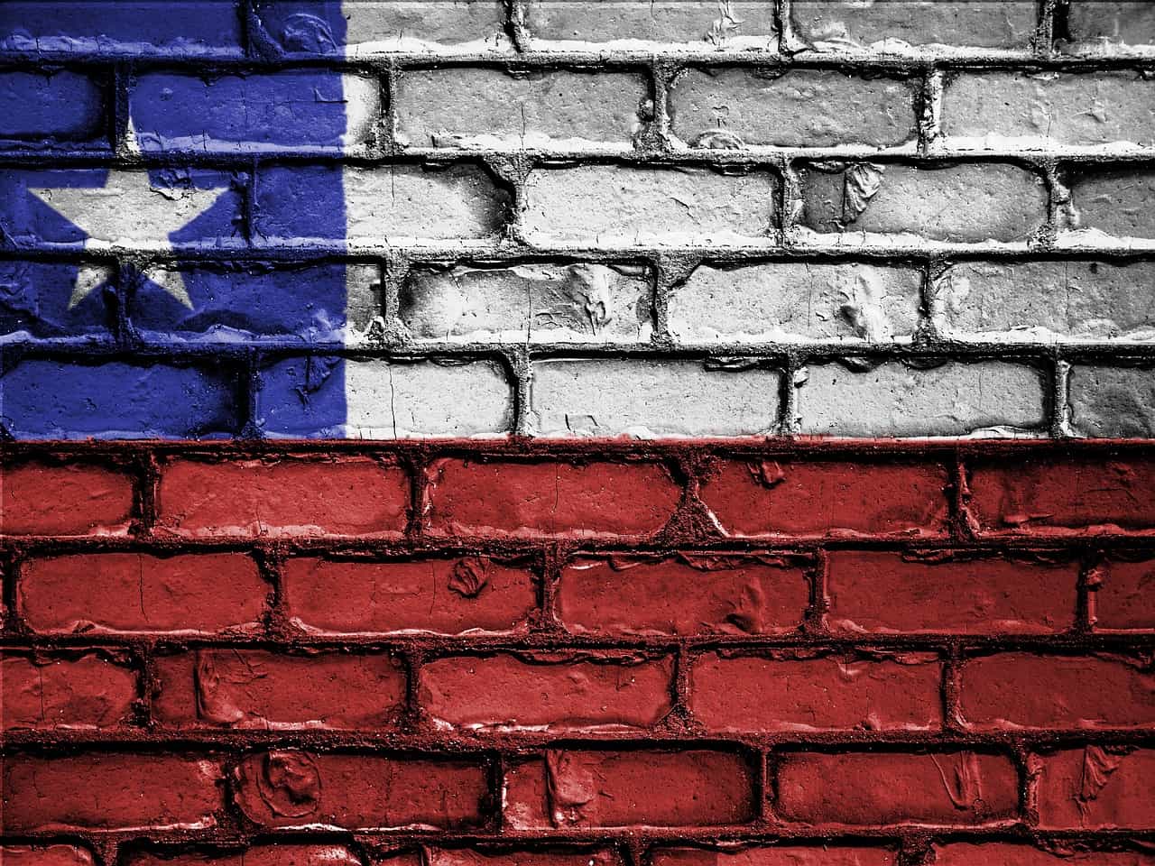 Bandera de Chile pintada sobre pared de ladrillo.