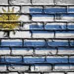Bandera de Uruguay pintada sobre pared de ladrillos.