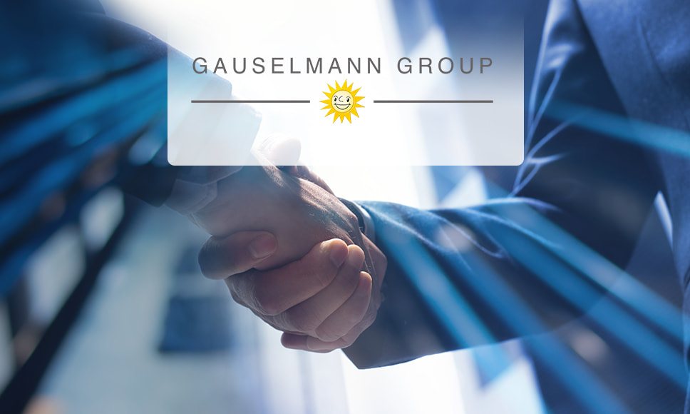 Dos hombres estrechando las manos con el logo del Grupo Gauselmann al frente.