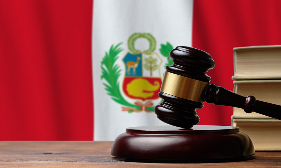 Mazo de juez y en el fondo la bandera de Perú.
