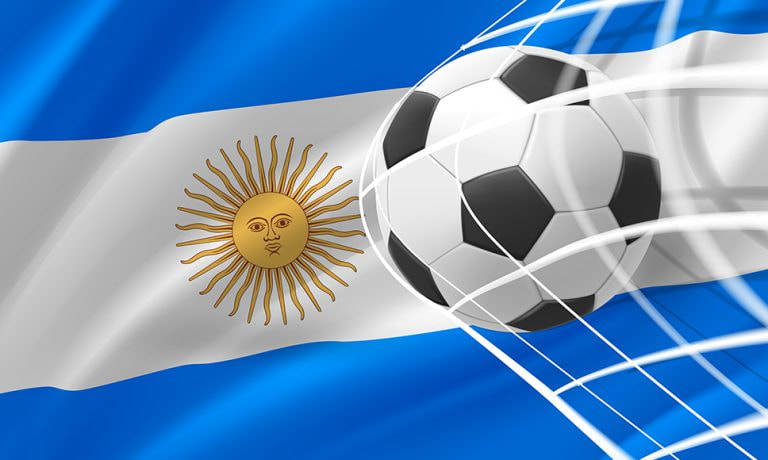 Red de una portería de fútbol con un balón sobre el trasfondo de la bandera argentina.