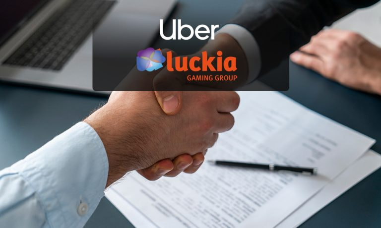 Apretón de manos en una oficia con los logos de Uber y de la casa de apuestas Luckia.