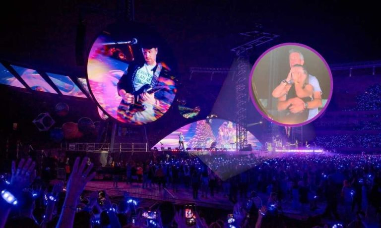 Pantalla gigante en concierto con pareja destacada por la Kiss Cam y público iluminado.