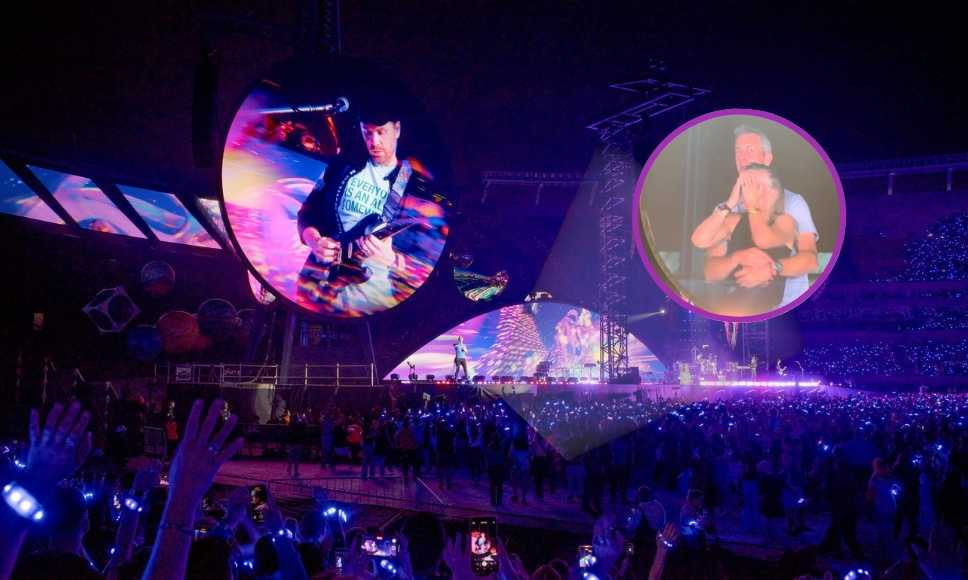 Pantalla gigante en concierto con pareja destacada por la Kiss Cam y público iluminado. 