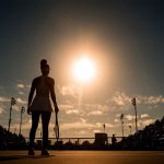 Una tenista con una raqueta sobre una pista de tenis con público.