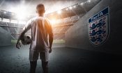 Futbolista Lucas Paquetá en túnel de estadio con balón, mirando el escudo de la FA