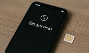 Teléfono móvil mostrando mensaje de “Sin servicio” junto a una tarjeta SIM sobre la mesa.