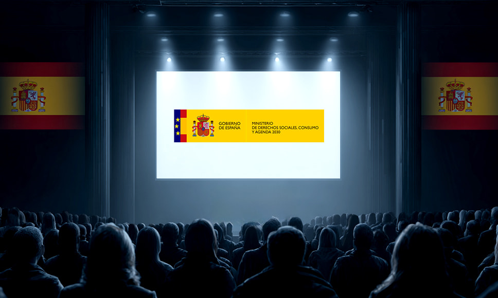 Auditorio con público observando una pantalla con el logotipo del Ministerio de Consumo de España.
