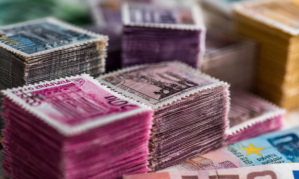 Montones de sellos de colores apilados junto a billetes de euro, símbolo del fraude del Fórum Filatélico.