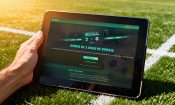 Pantalla de un tablet en un campo de fútbol con la promoción “Oferta de 2 goles de ventaja” de bet365 en pantalla.