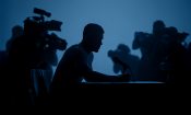 Silueta de un hombre sentado ante un micrófono durante una rueda de prensa.