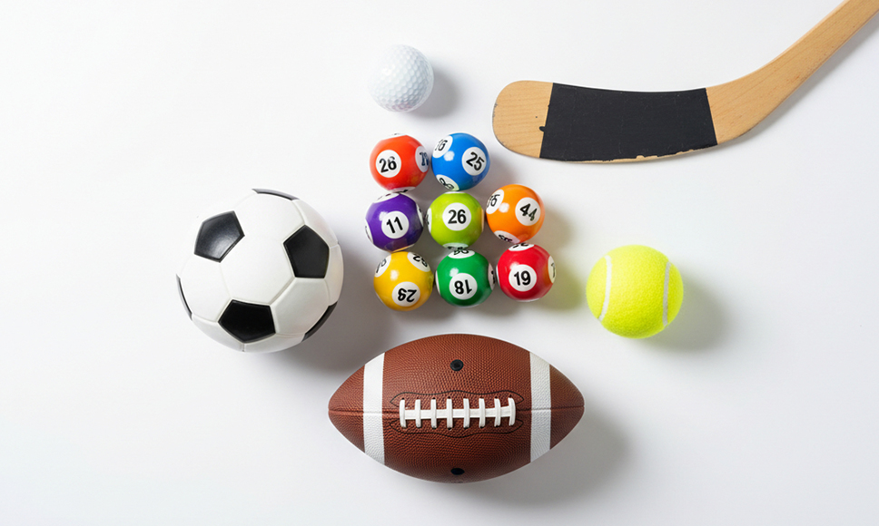 Balones deportivos, bolas de lotería y taco sobre fondo blanco.
