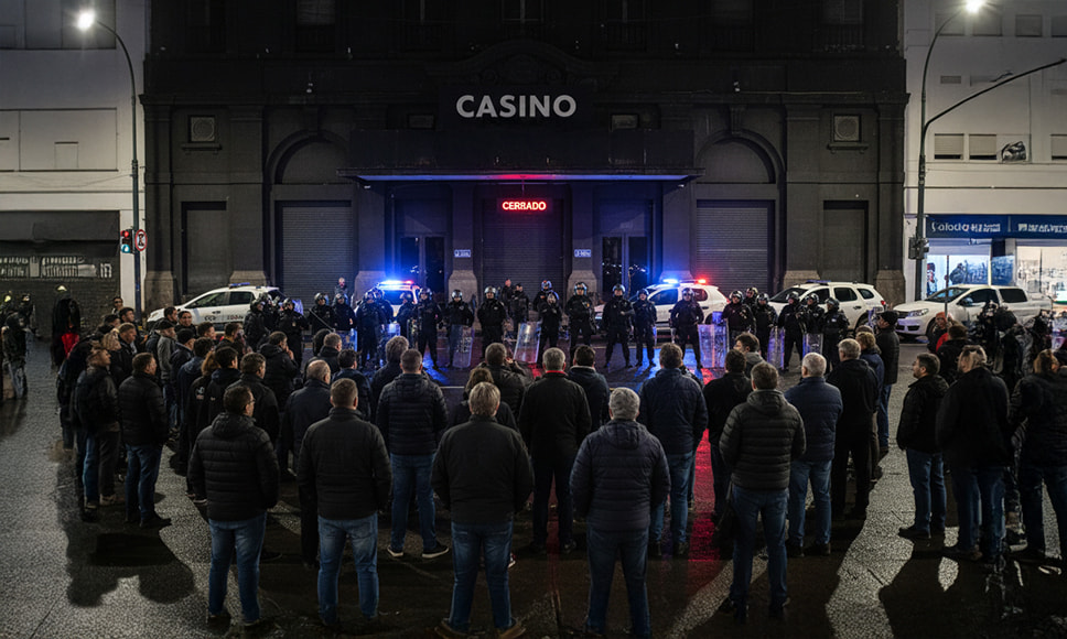 Protesta de trabajadores frente a un casino cerrado con presencia policial.