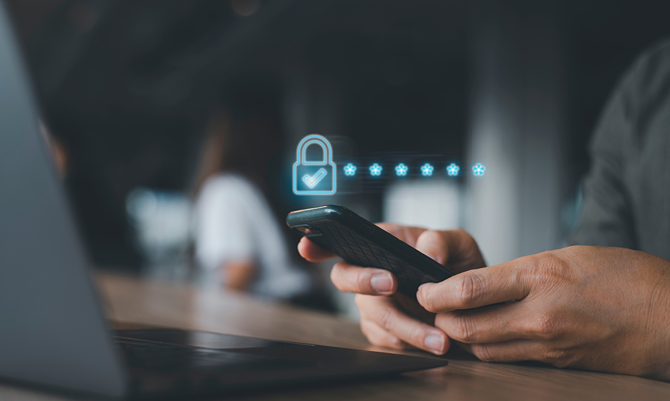 Una mano poniendo una contraseña que aparece como asteriscos al lado de un candado