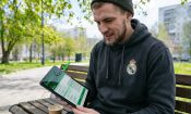 Hombre sentado en un banco usando una tablet con página de apuestas deportivas visible