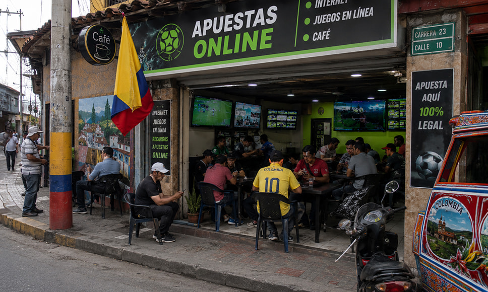 Personas en local de apuestas online viendo partidos y realizando apuestas deportivas.