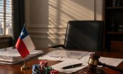 Una mesa de despacho con la bandera de Chile, fichas de casino y un mazo de juez