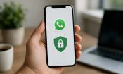 Persona sosteniendo un móvil con el logo de WhatsApp y un icono de seguridad en la pantalla.