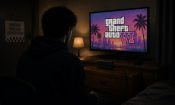 Un joven de espaldas, mirando la pantalla de un videojuego a oscuras.