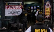 Policías peruanos colocan un cartel de clausura en la entrada de una sala de tragamonedas ilegal.