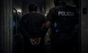Agente de policía escoltando a un detenido con iconos de criptomonedas y ciberseguridad superpuestos.