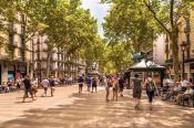 Turistas caminan por una zona concurrida de España con mochilas y bolsos.