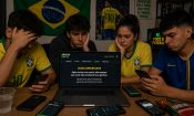 Jóvenes con camisetas de Brasil ante un portátil con el aviso de una casa de apuestas que no pagará sus ganancias.