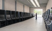 Nave industrial con filas de tragamonedas apagadas y un agente policial inspeccionándolas, del operativo contra el CJNG en el Edomex.
