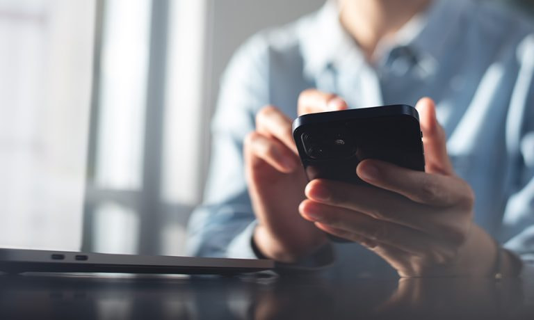 Persona con camisa de oficina sosteniendo su móvil, sobre el bloqueo de SMS bancarios con alias falso en España.