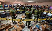 Agentes de policía junto a máquinas tragamonedas y cajas de dinero incautado en un operativo de Coljuegos contra el juego ilegal.