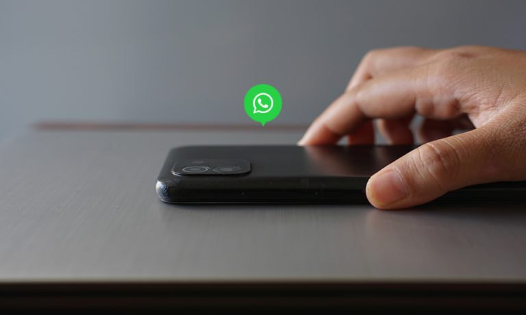 Mano acercándose a un móvil con el icono de WhatsApp flotando, sobre el ataque zero-click que hackea la app.