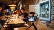 Restaurante bufé grabado con un móvil para redes sociales junto a un cuadro eléctrico con cables manipulados.