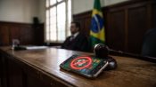 Móvil con una app de apuestas de fútbol bloqueada junto a un mazo de juez en un tribunal de Brasil.